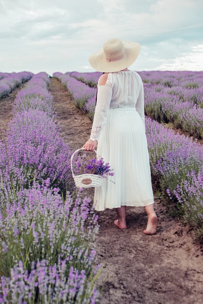 White woman carrying a basket on the purple flower bed during the day to walk
